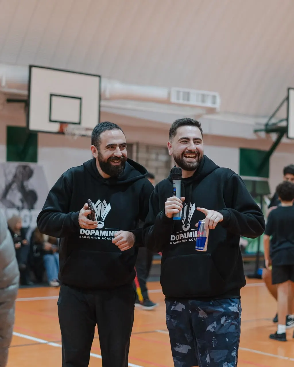 Dopamine coaches laughing on court in branded hoodies