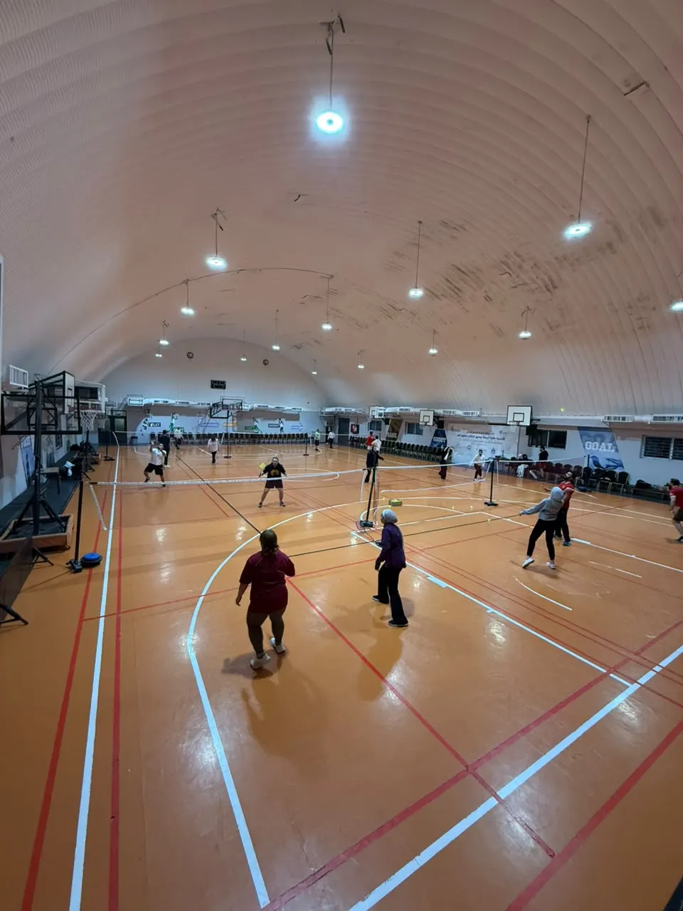Players training on multiple courts inside the Dopamine badminton hall
